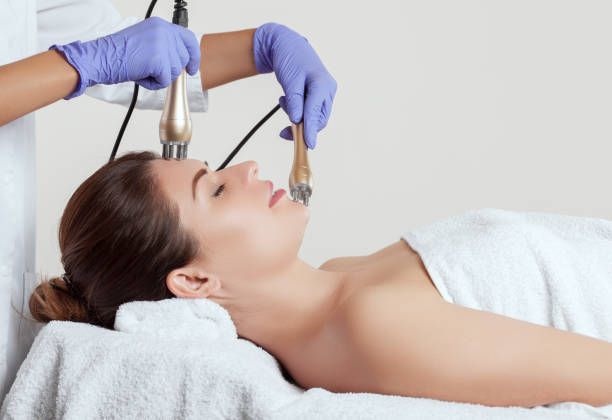 Woman receiving a facial massage, eyes closed, covered in a white towel in a spa.