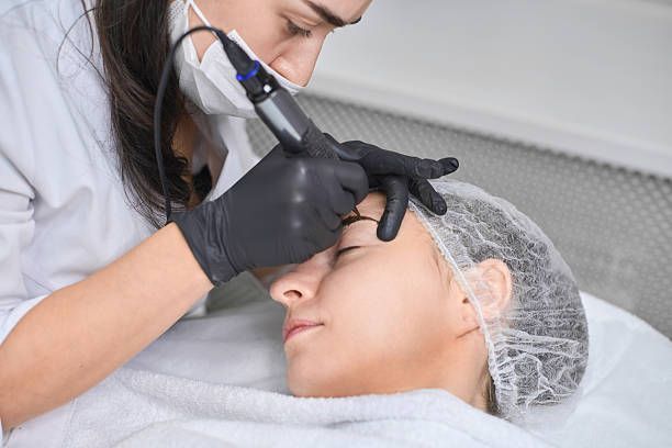 A person getting their eyebrow makeup done by another person with a thin brush, indoors.
