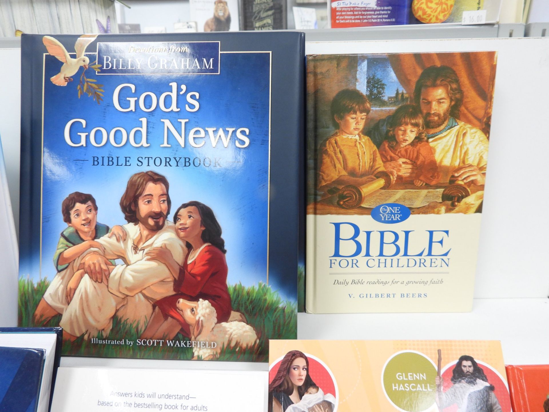 Two children's Bible storybooks on a shelf; one by Billy Graham, featuring Jesus and children.