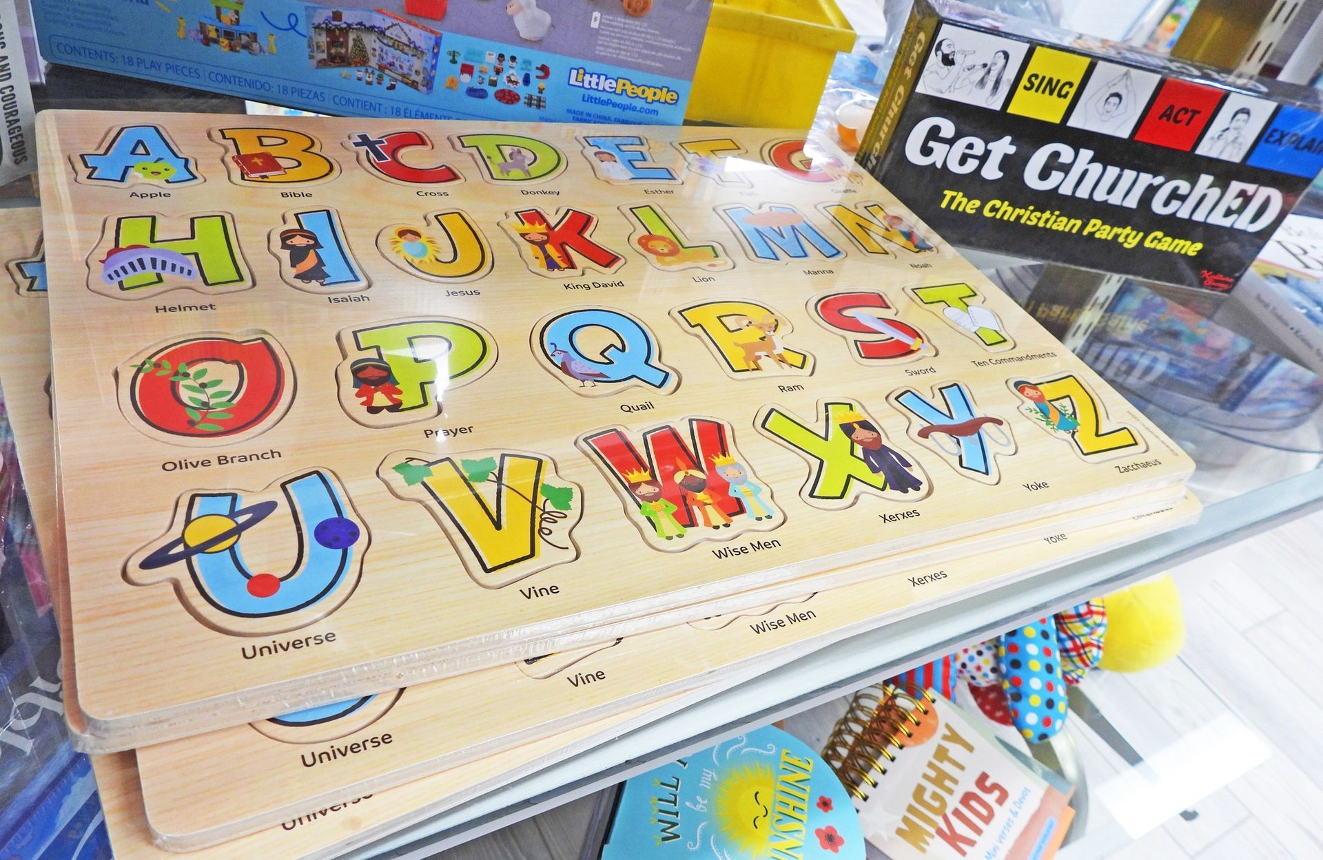 Wooden alphabet puzzle with colorful letters, stacked on shelf with other items.