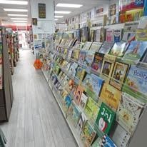 Bookshelves in a bookstore, stocked with books. Shelves run alongside a long aisle.