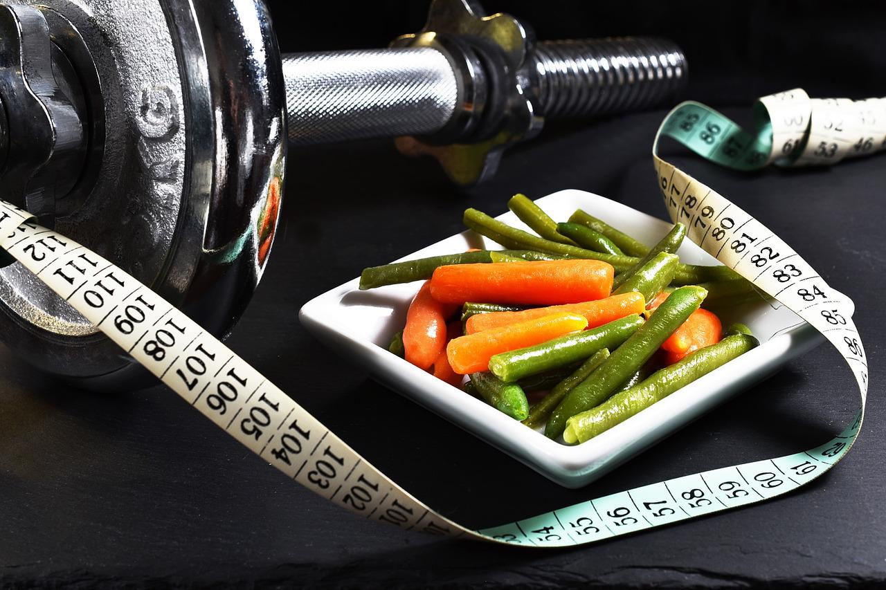 Plate of carrots and peas next to tape measure and barbell link reads 