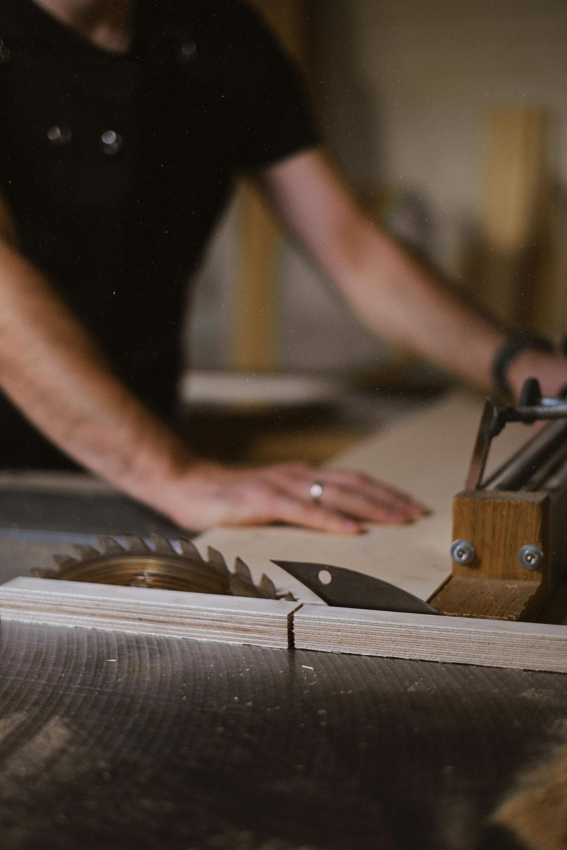 Person cutting wood with a table saw in a workshop.
