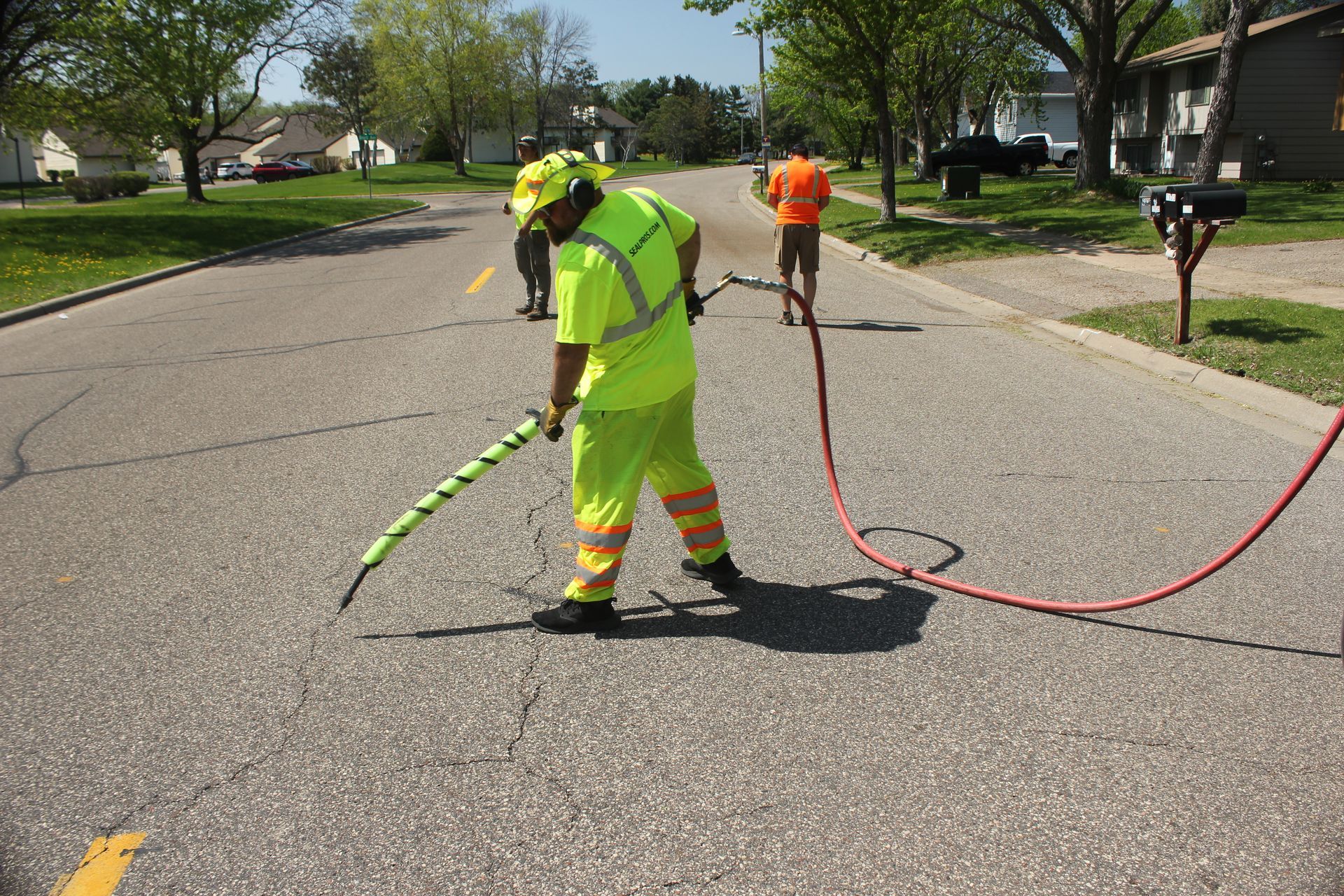 A person is applying blue paint to a concrete surface with a roller.