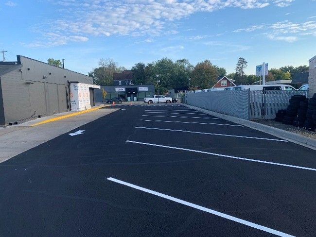 A black sealcoat is being applied on a sunny day by a professional sealcoating company.