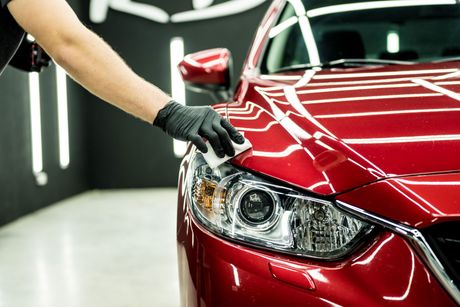 A person is polishing a red car in a garage.