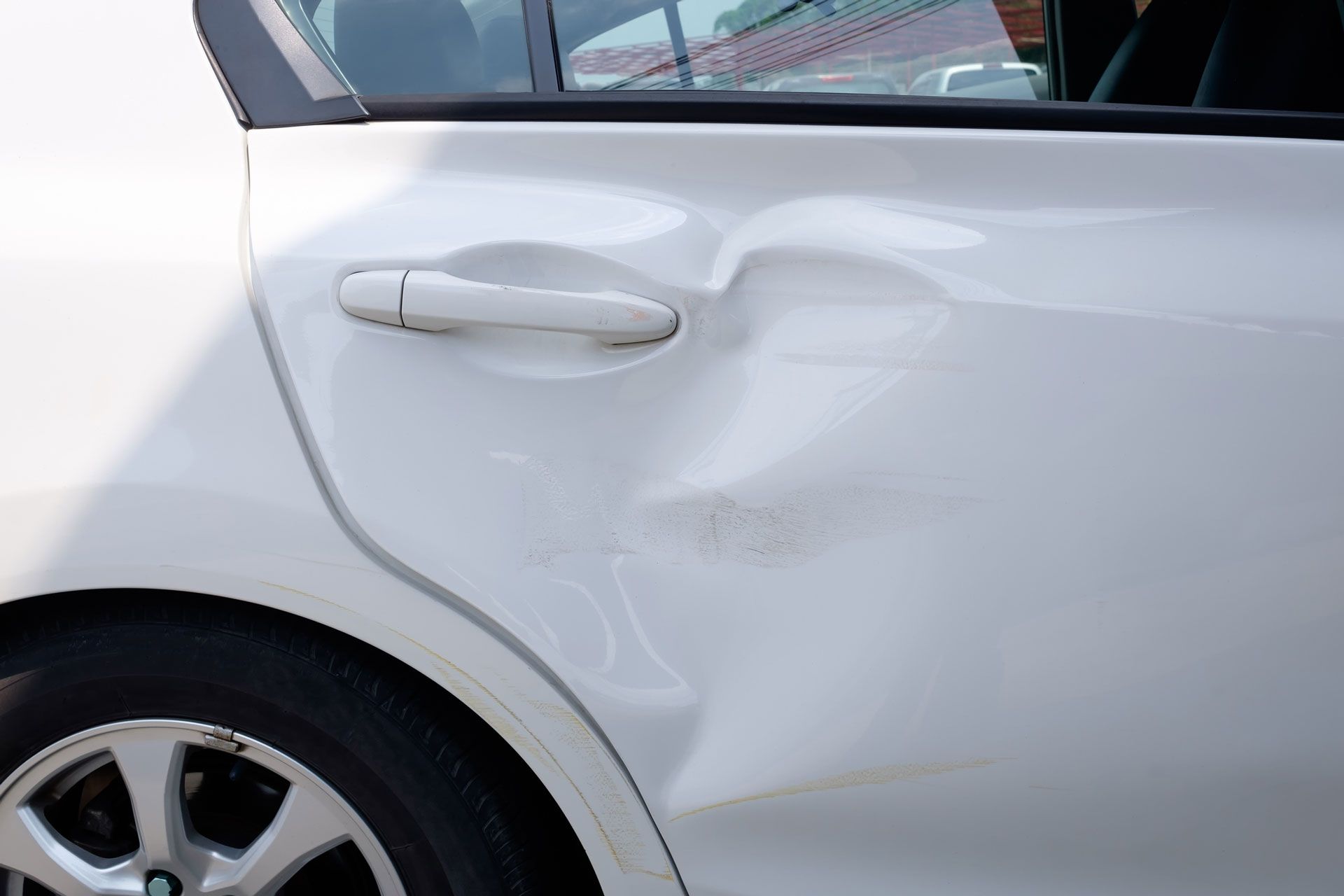A close up of a white car with a damaged door.