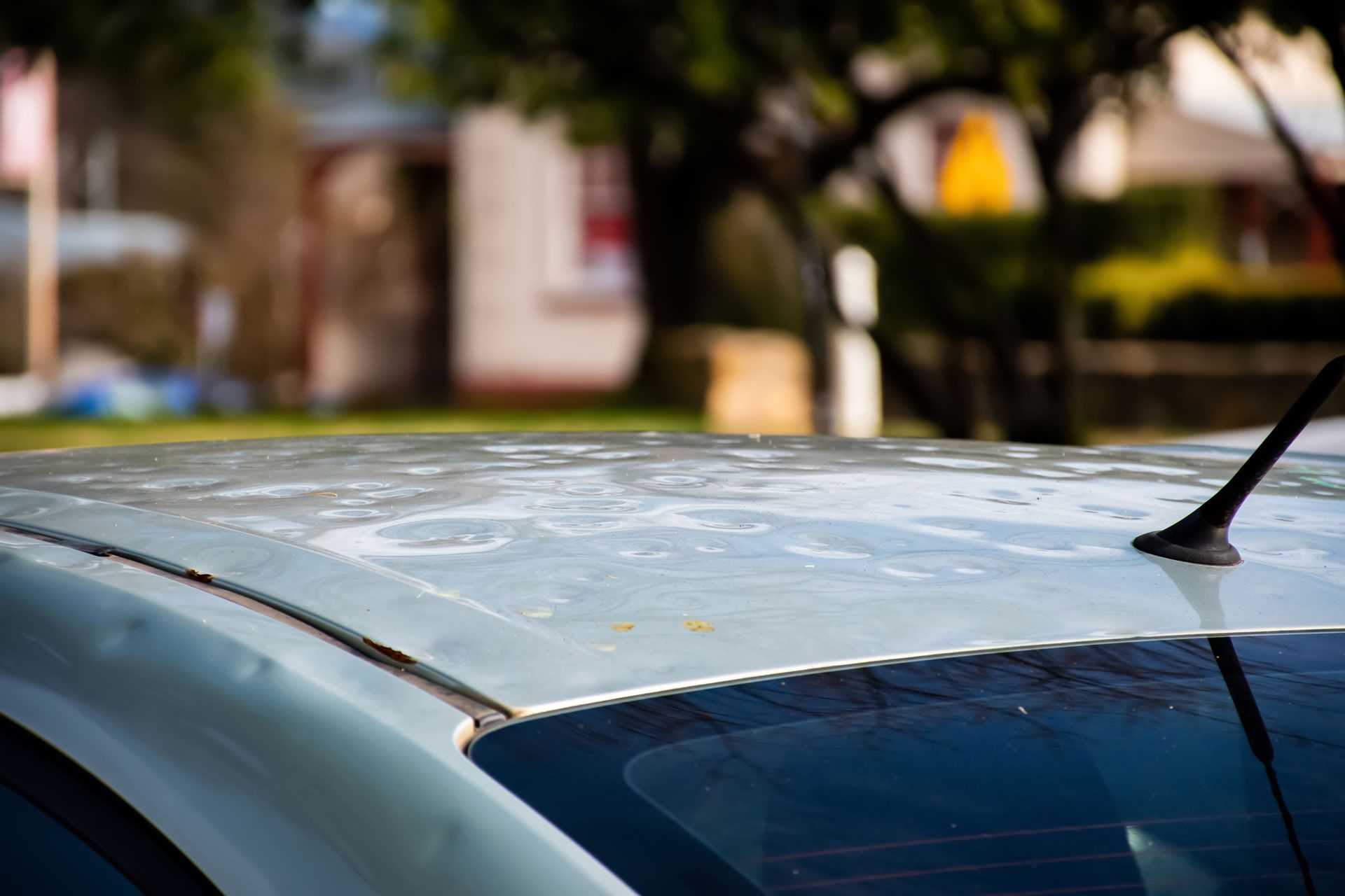 A close up of the roof of a car with a antenna on it.