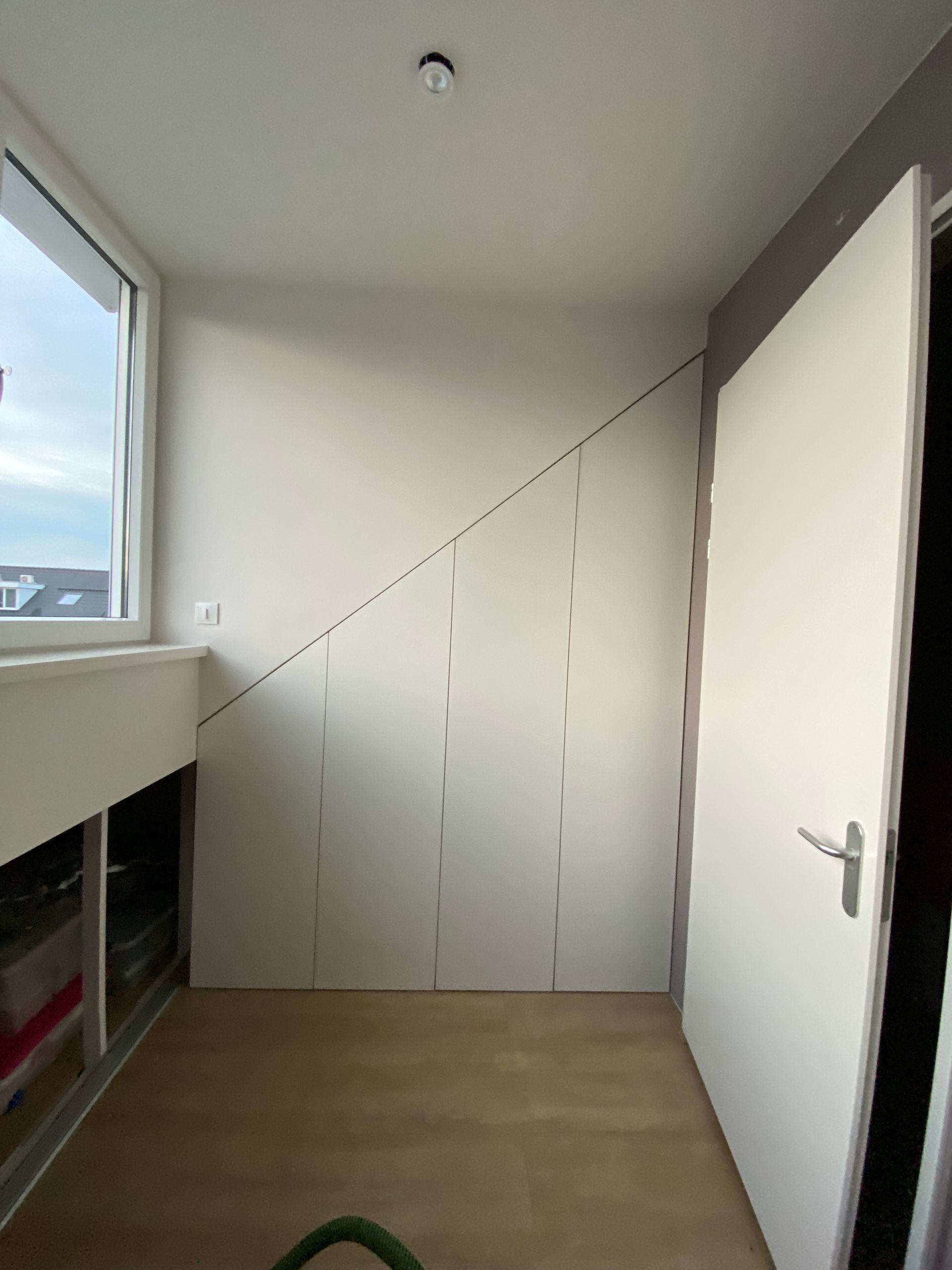 Een inbouwkast onder een schuine kap om kleding in op te slaan.