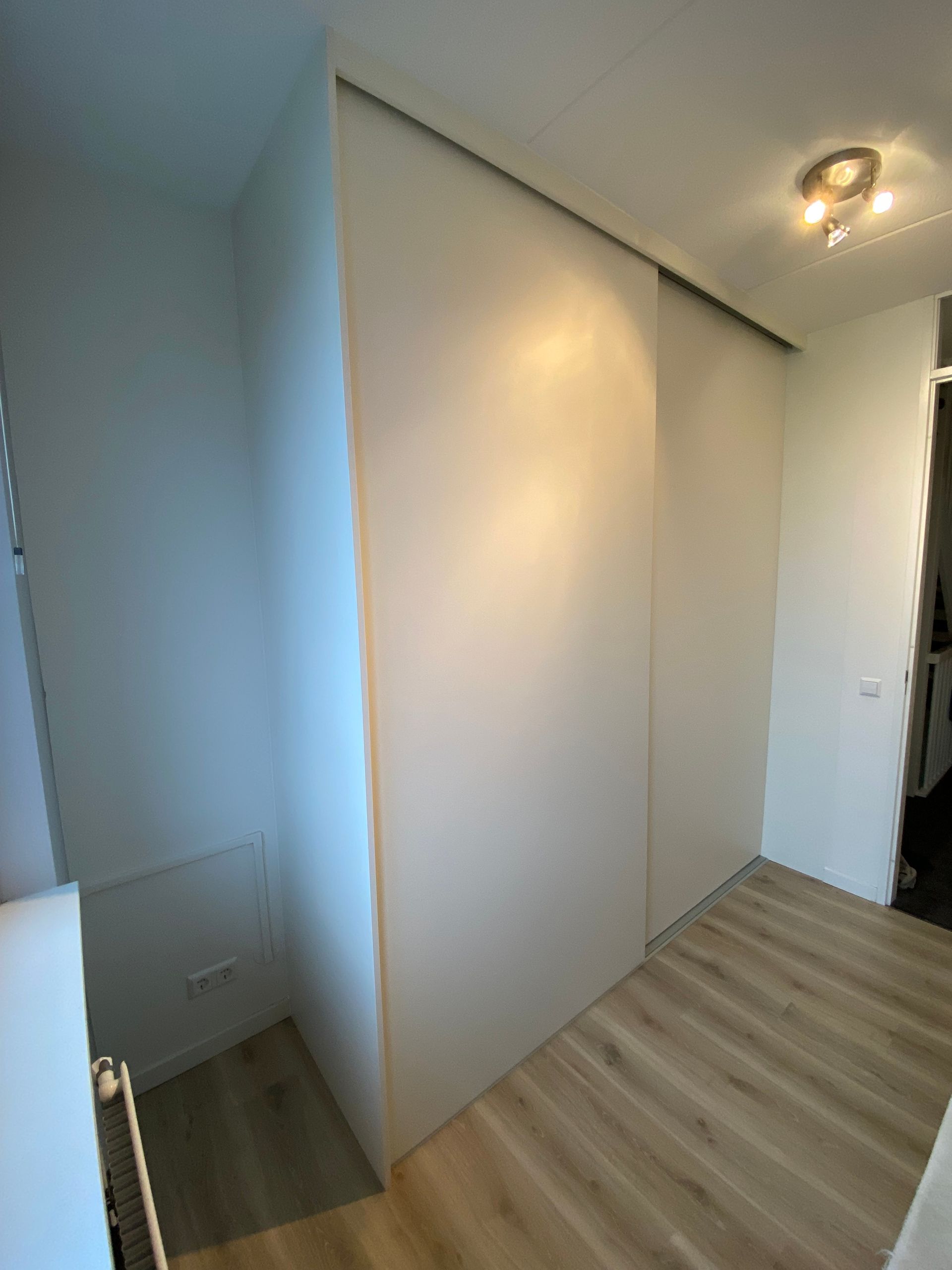 Een inbouwkast met schuifdeuren en lades om kleding in op te slaan.