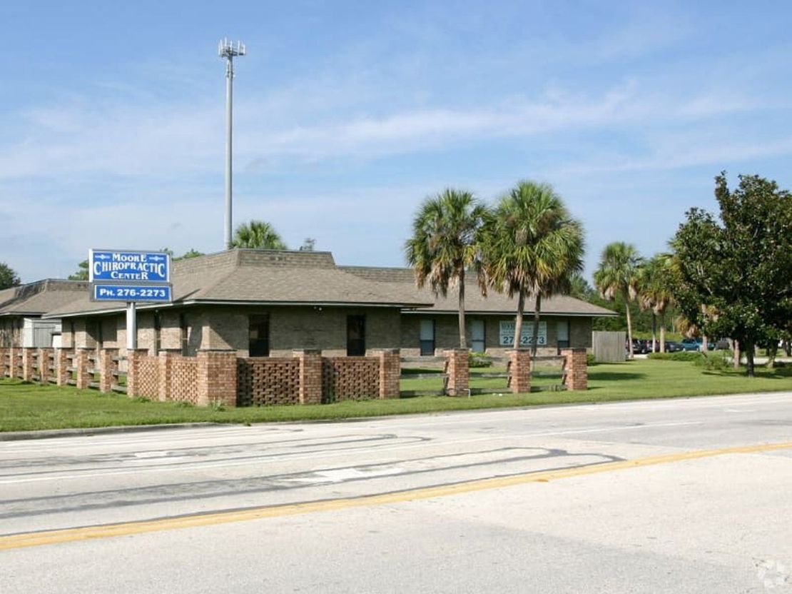Building with sign: Medical center, low brick wall, palm trees, sunny day.