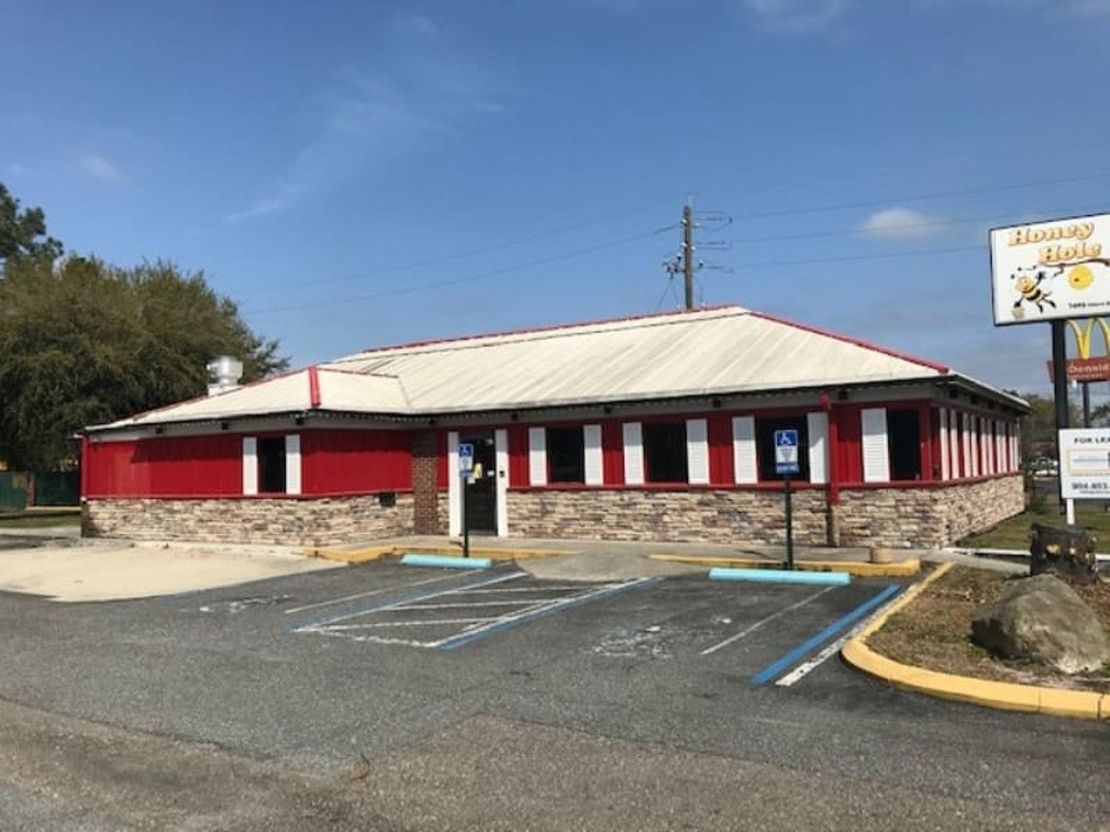 Red and white diner with parking spots and a sign; sunny day.
