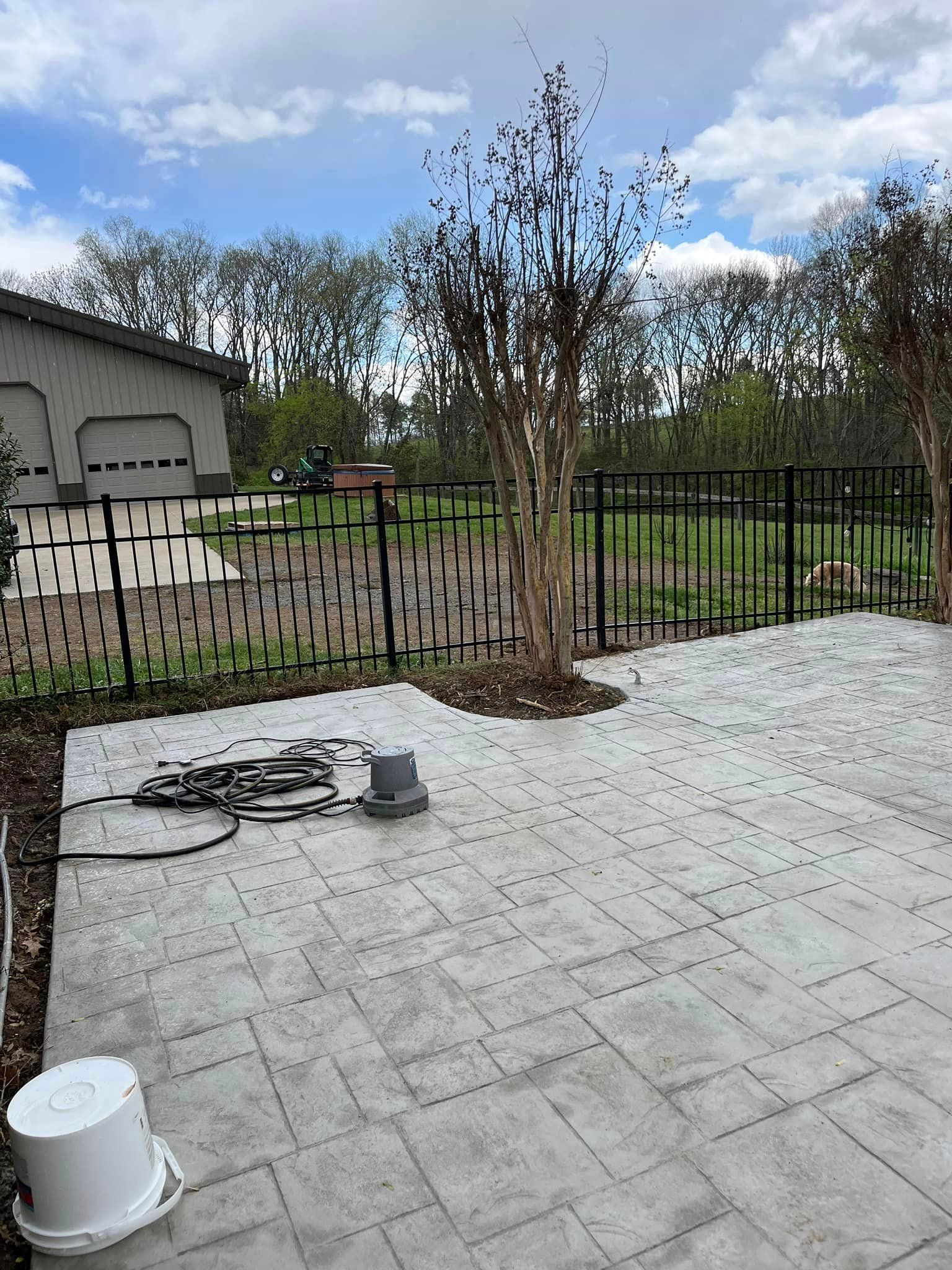 A patio with a fence and a house in the background.