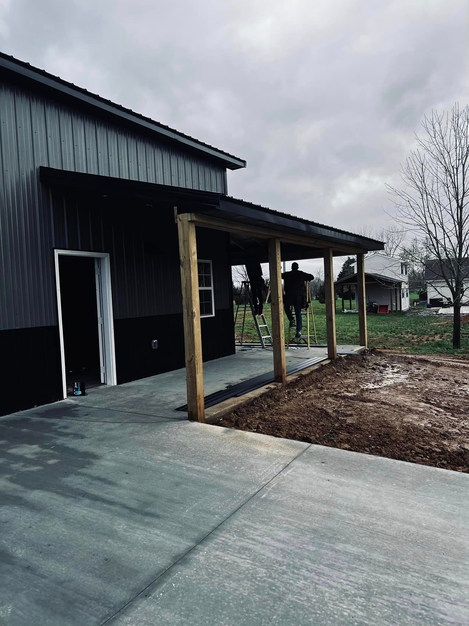 A black building with a covered porch in front of it.