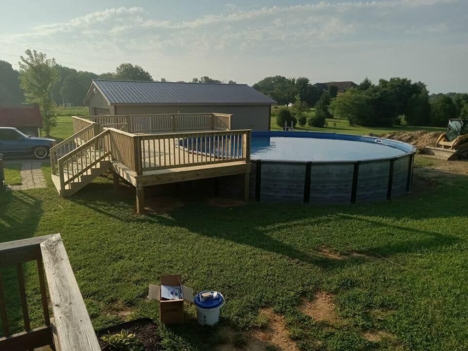 A large swimming pool with a wooden deck next to it.