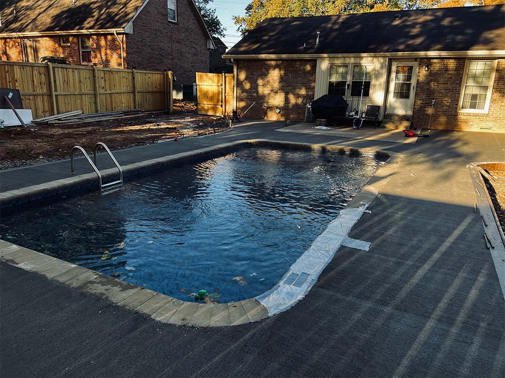 A large swimming pool is in the backyard of a house.