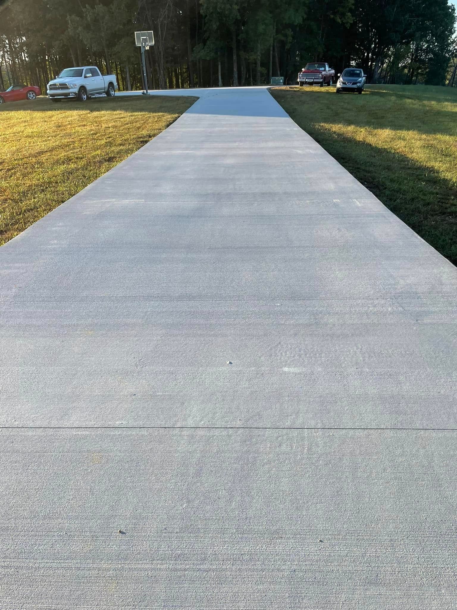 A concrete walkway leading to a parking lot with cars parked on the side of it.
