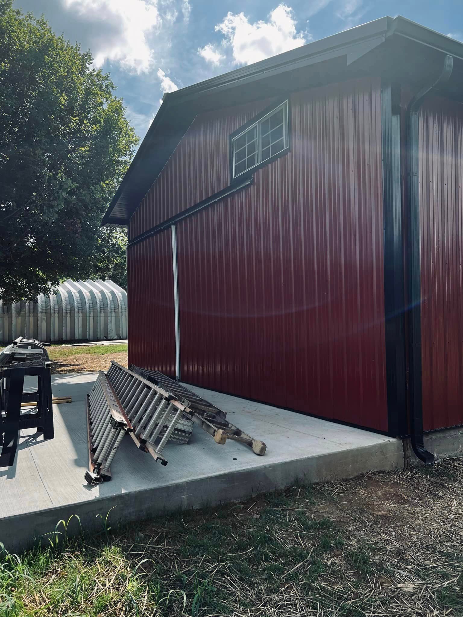 A red shed with a lot of wood in front of it.