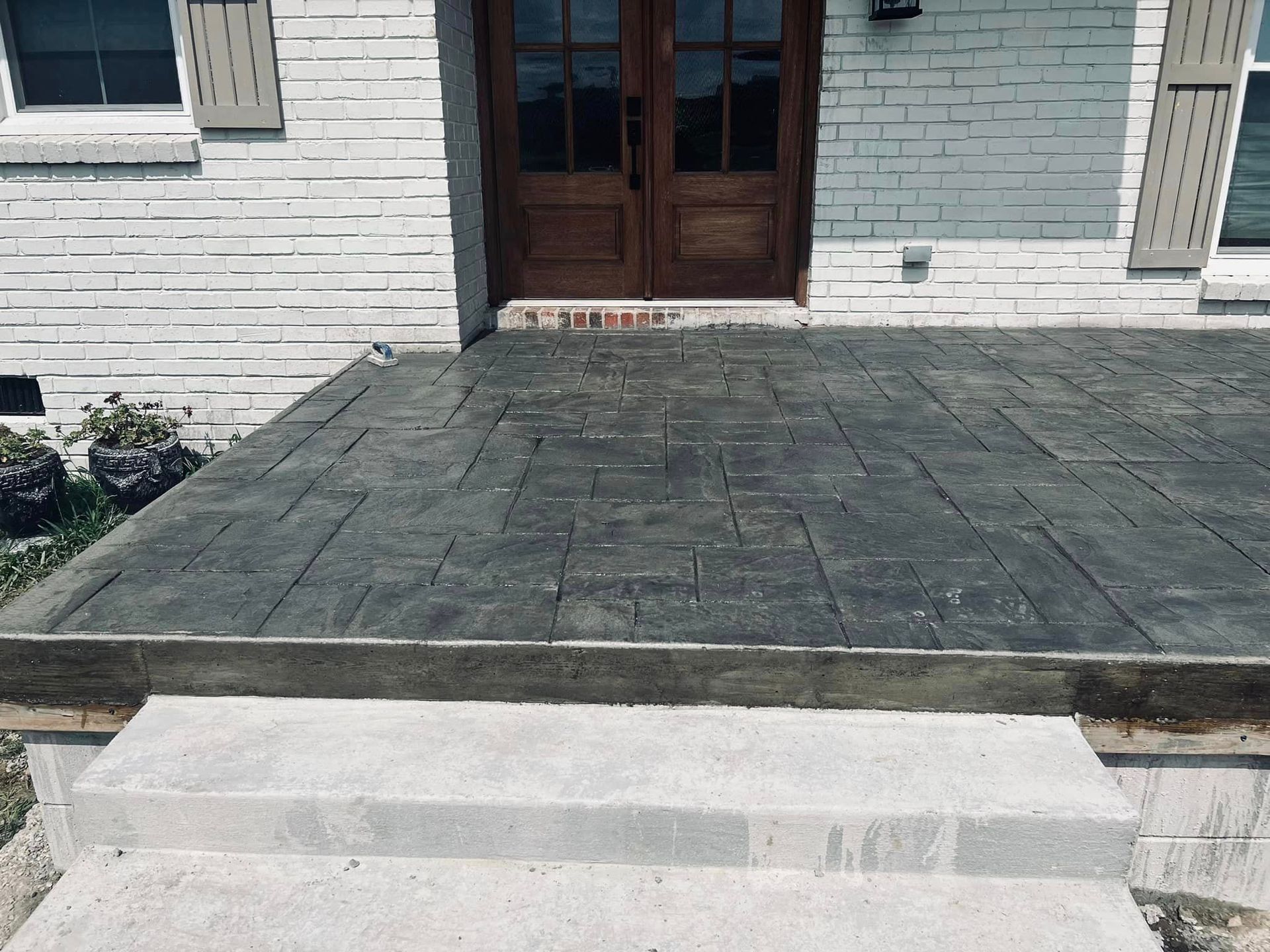 A brick house with a concrete porch and stairs in front of it.