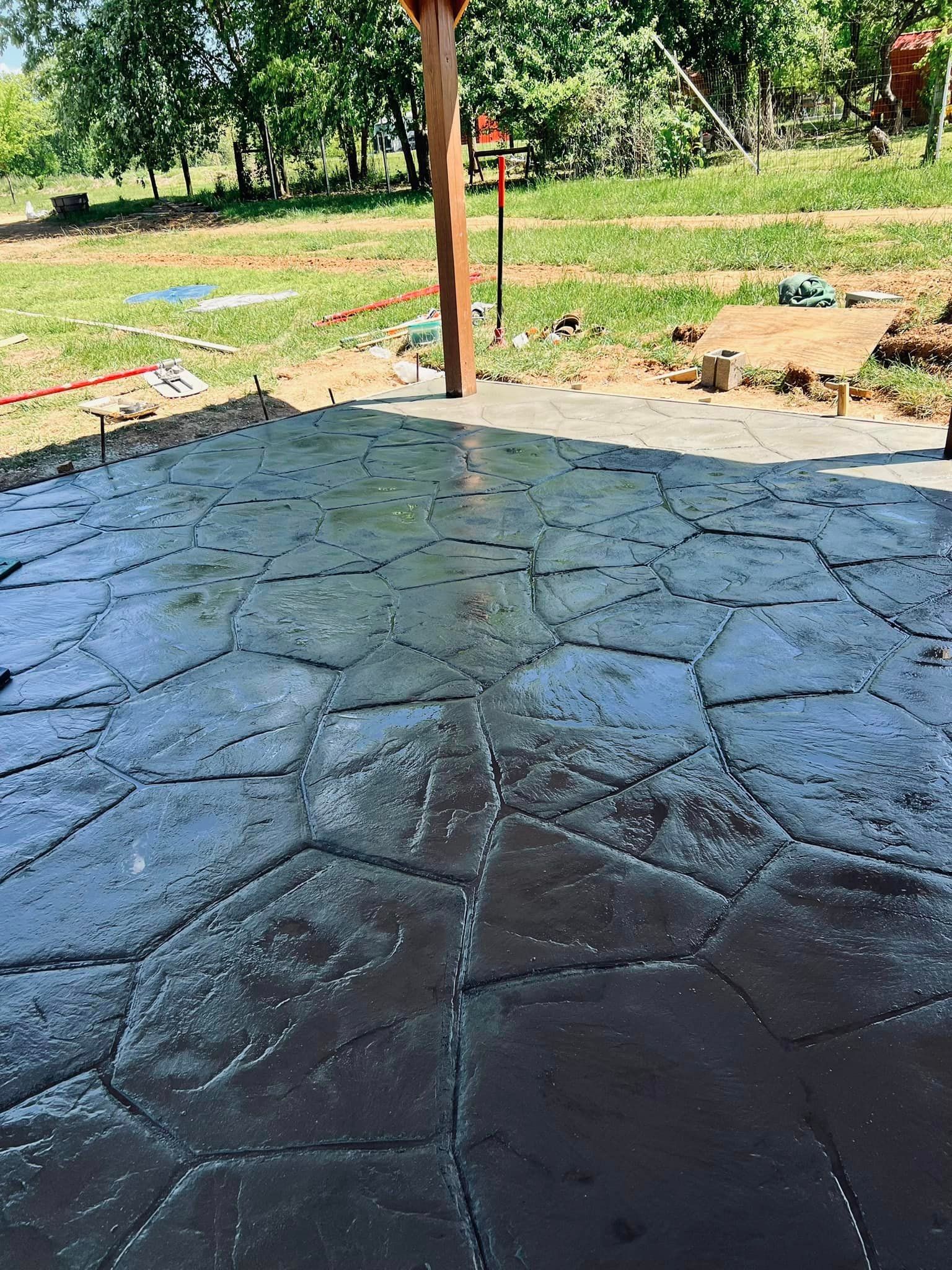 A concrete patio with a wooden post in the background and trees in the background.