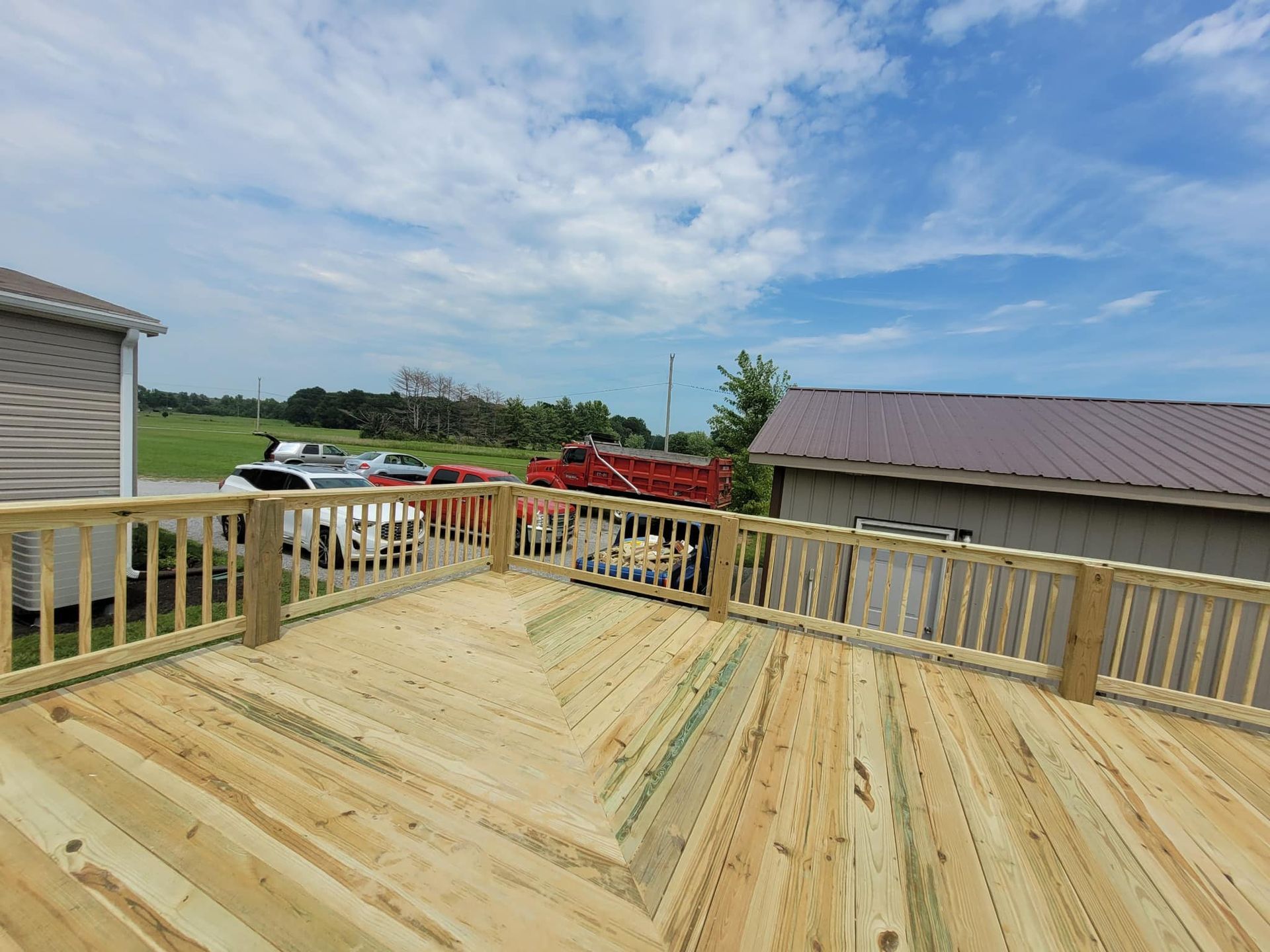 A wooden deck with a railing is being built on top of a house.