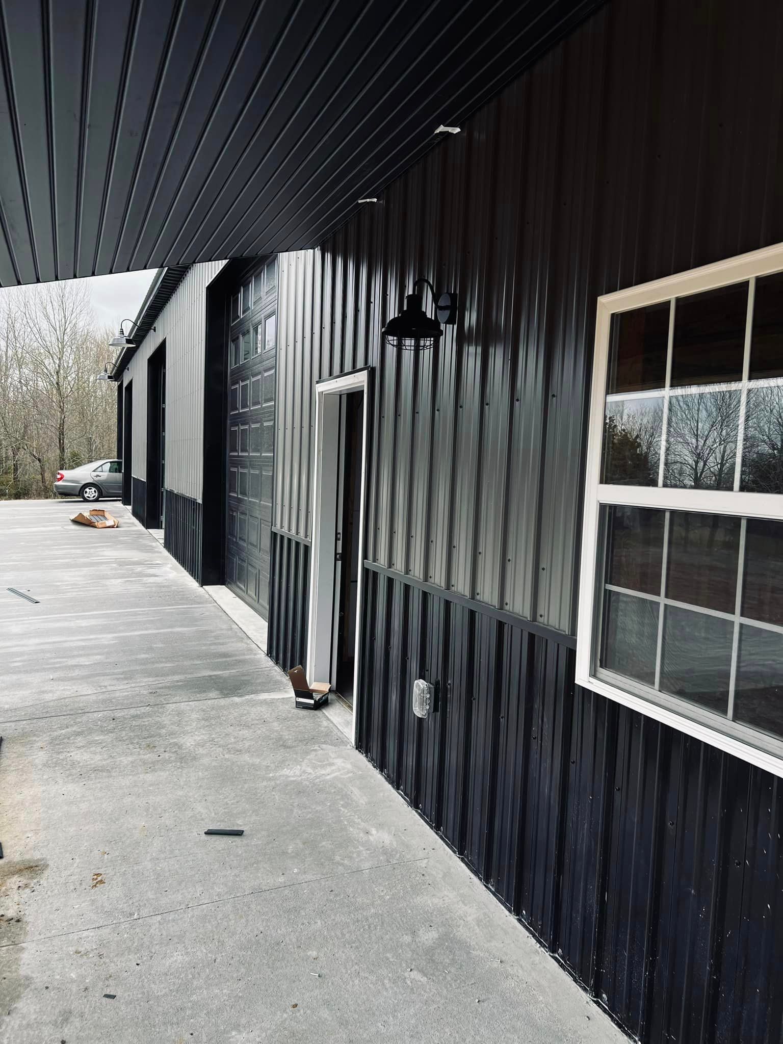 A black building with white windows and a car parked in front of it.
