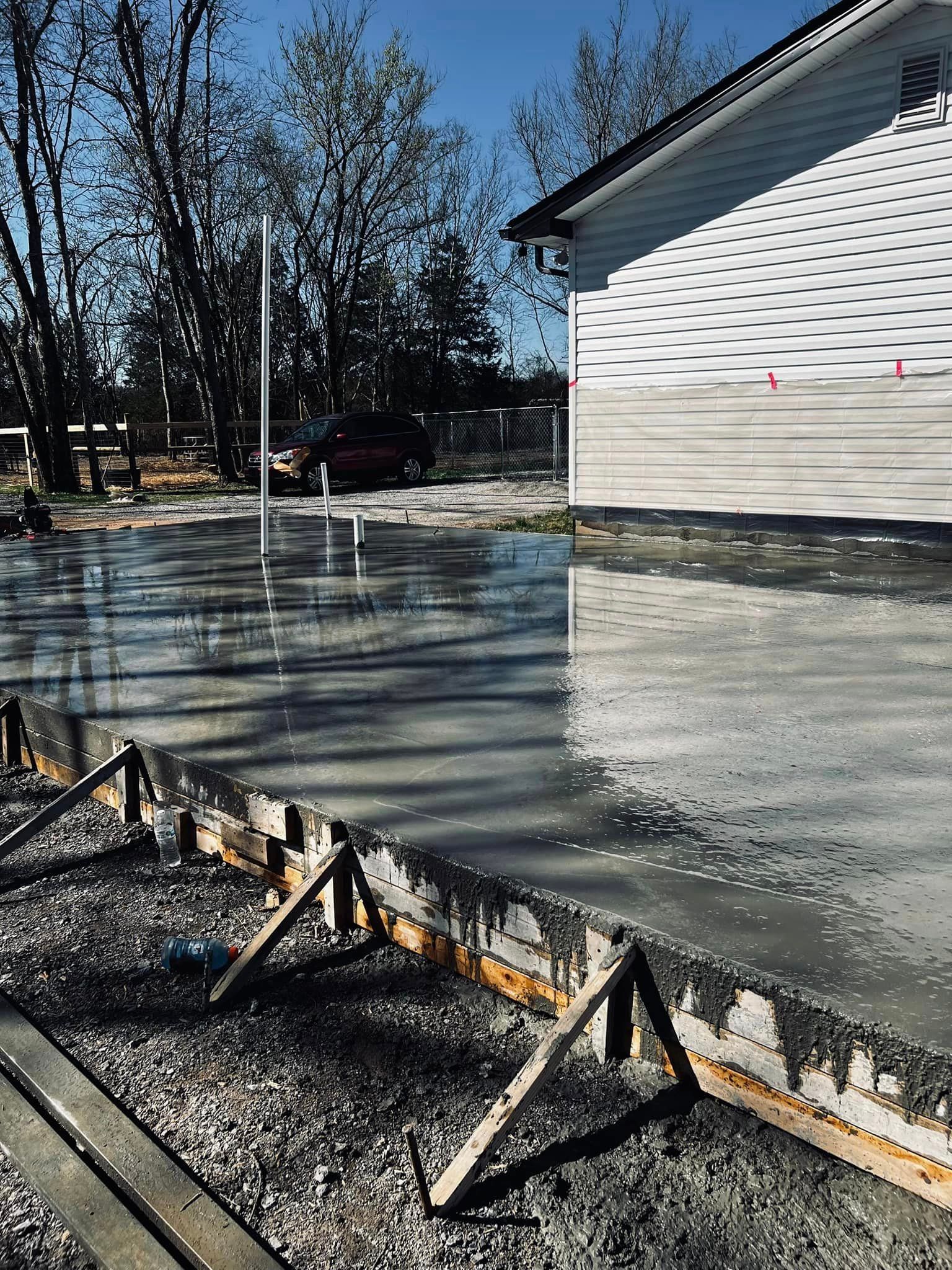 A concrete driveway is being built in front of a house.