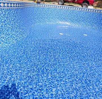 A blue swimming pool with a red truck parked in the background.