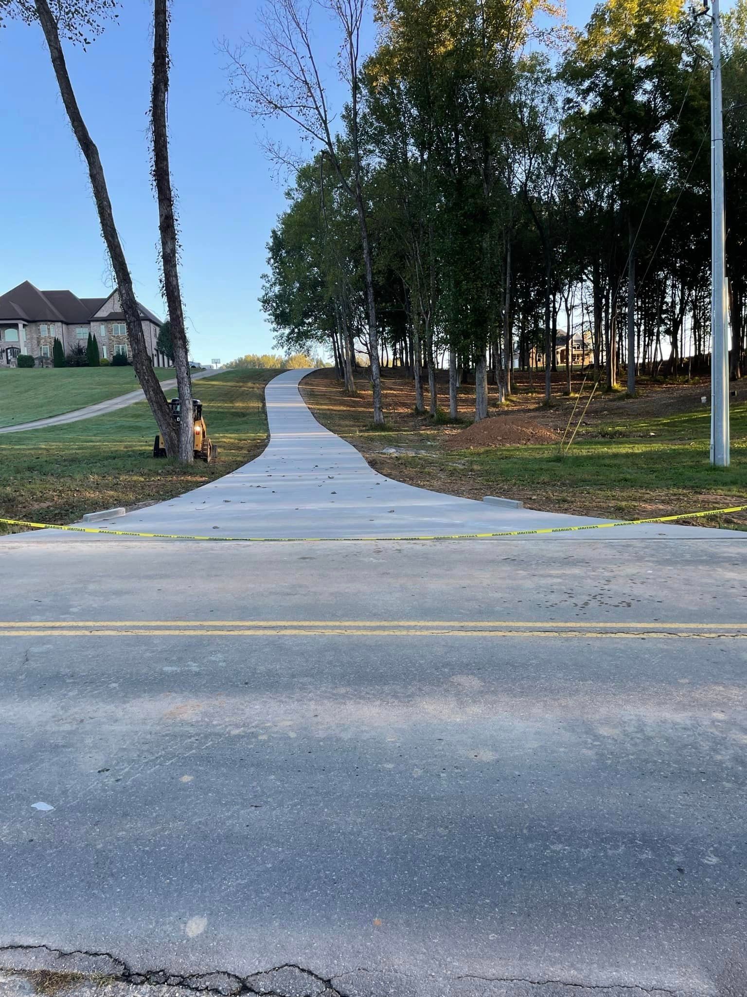 A concrete walkway leading to a house surrounded by trees