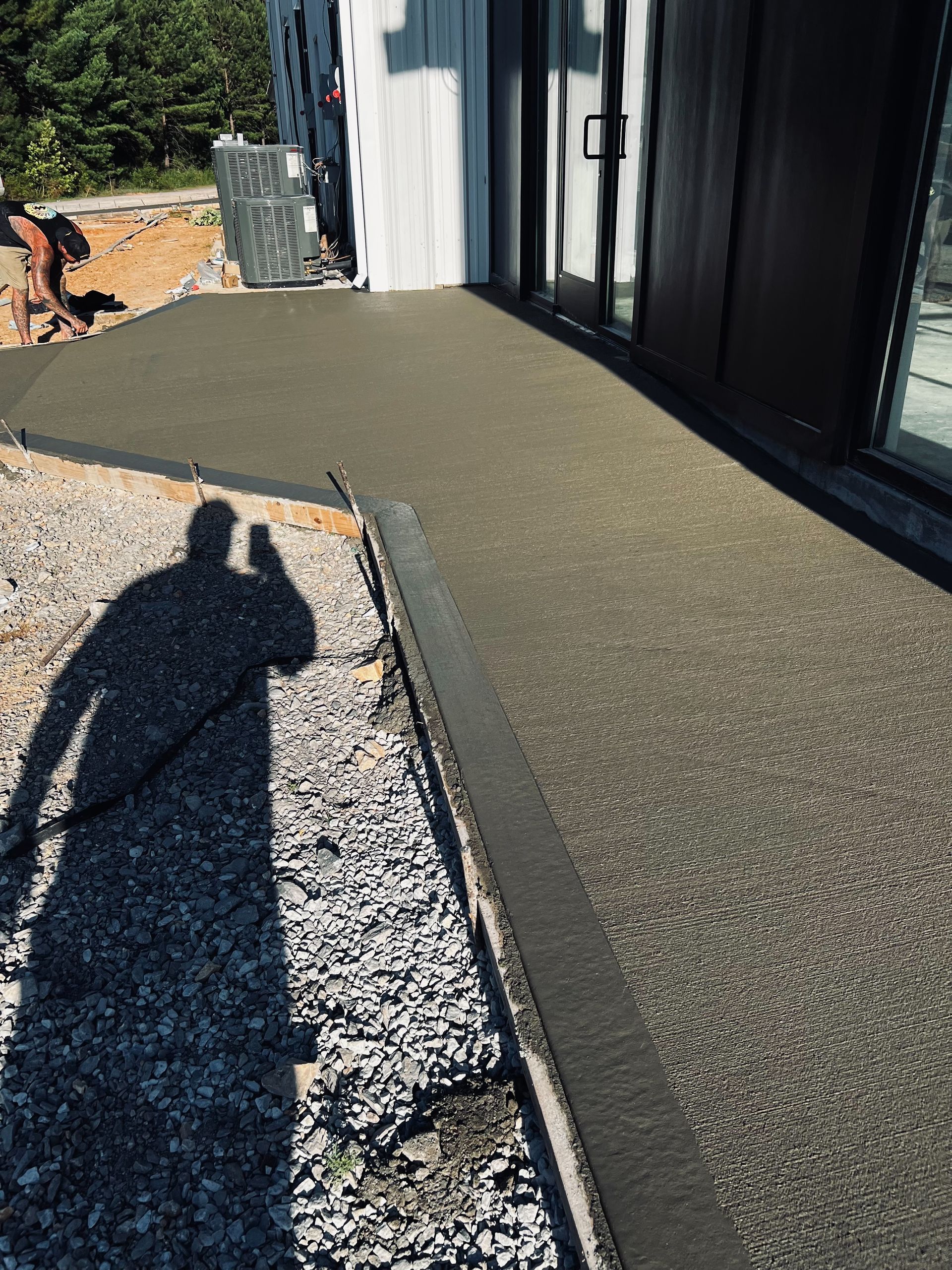 A shadow of a person is cast on a concrete walkway