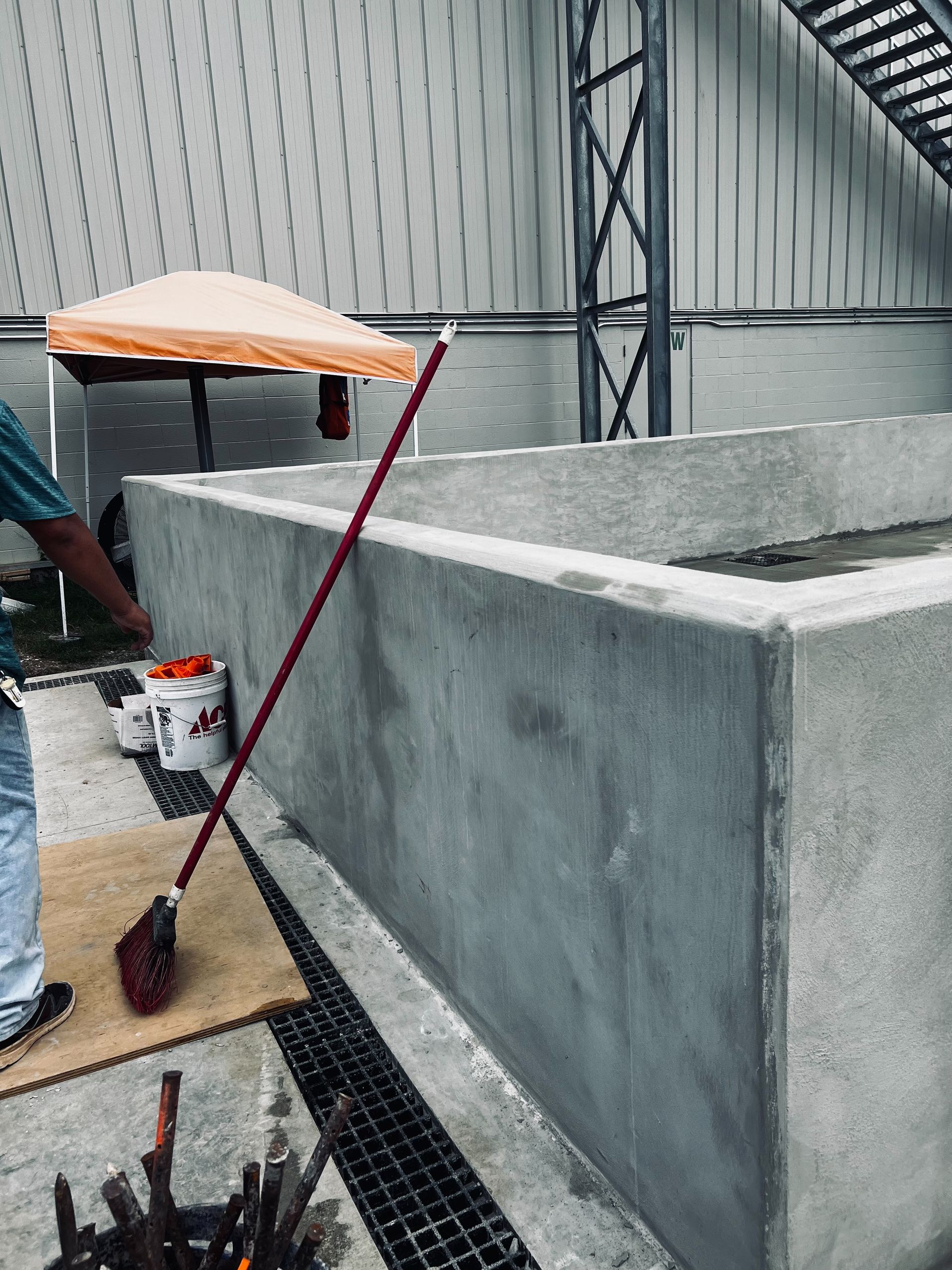 A man is cleaning a concrete wall with a broom