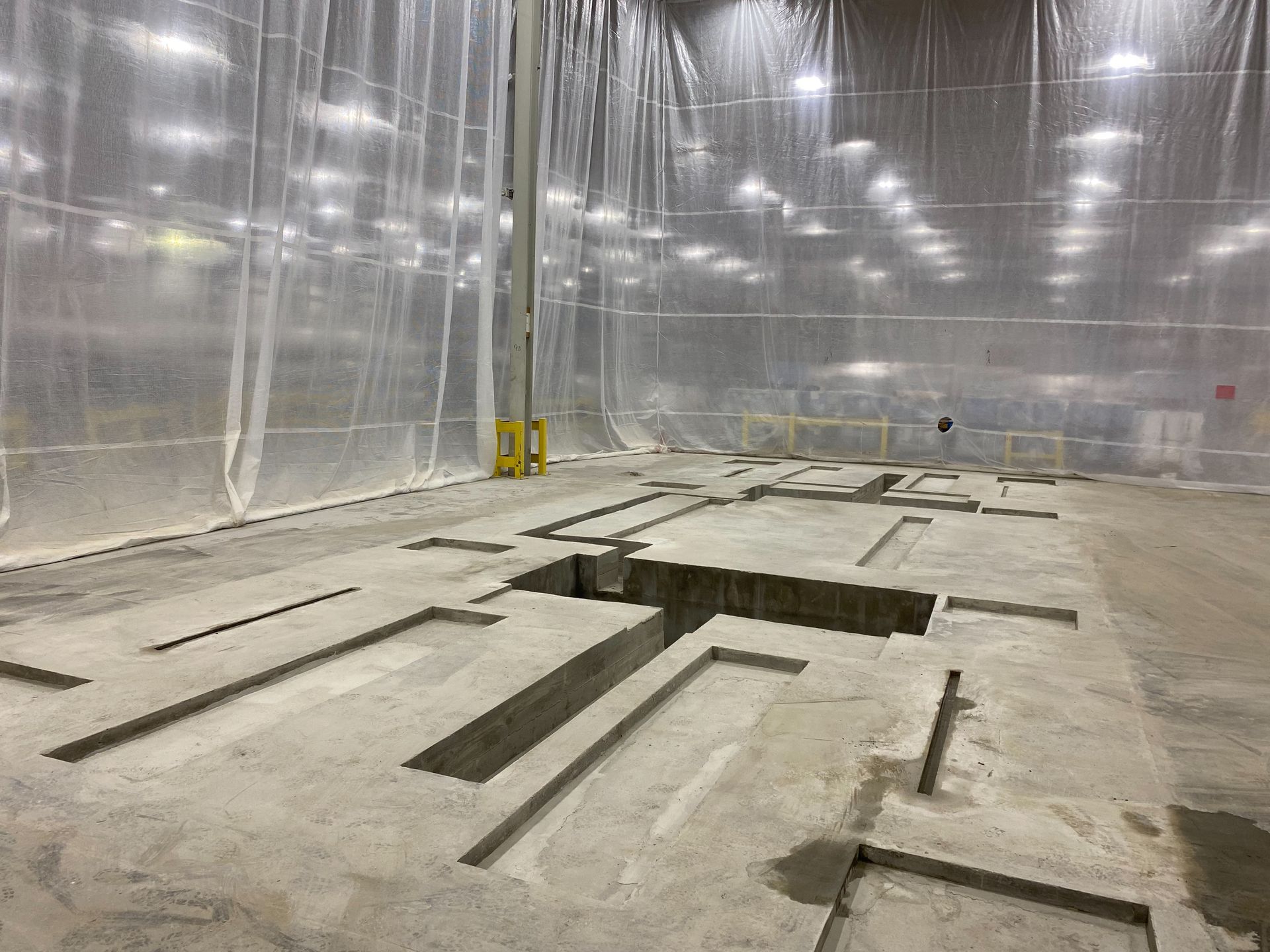 A large warehouse with a lot of concrete and a hole in the floor.