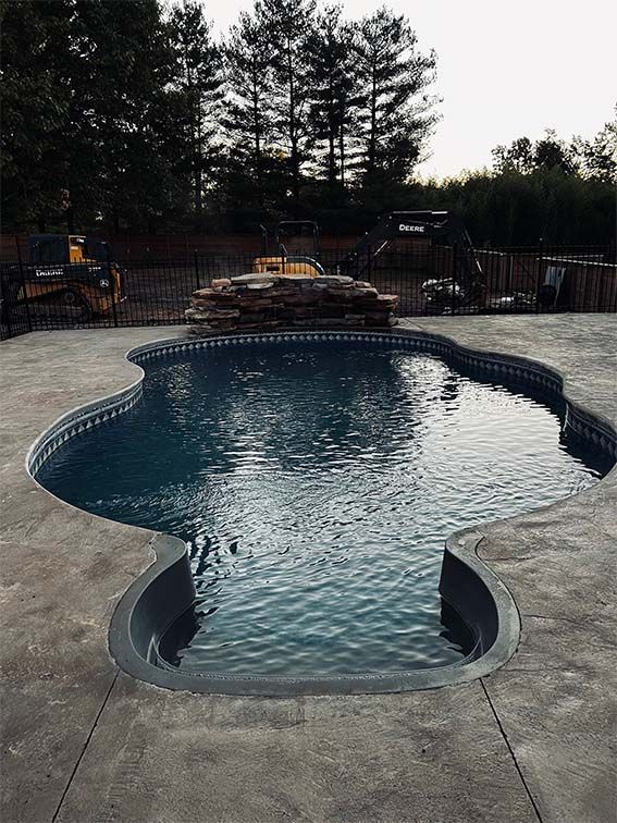 A large swimming pool in a backyard with trees in the background