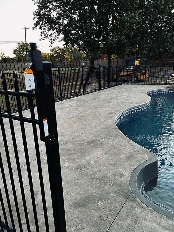 A black fence surrounds a large swimming pool.