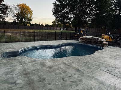 A large swimming pool is surrounded by a fence in a backyard.
