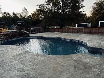 A large swimming pool is sitting on top of a concrete patio.