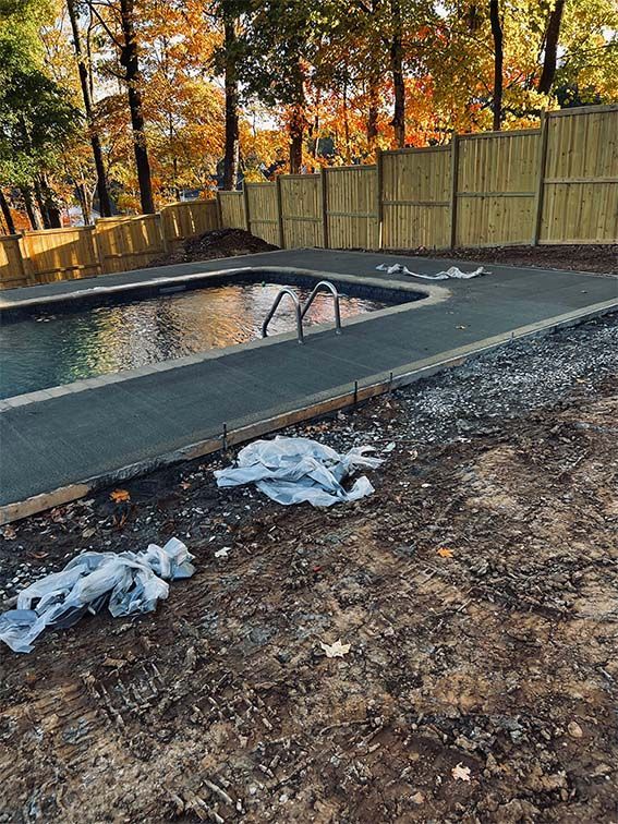 A swimming pool is being built in a backyard with a wooden fence.