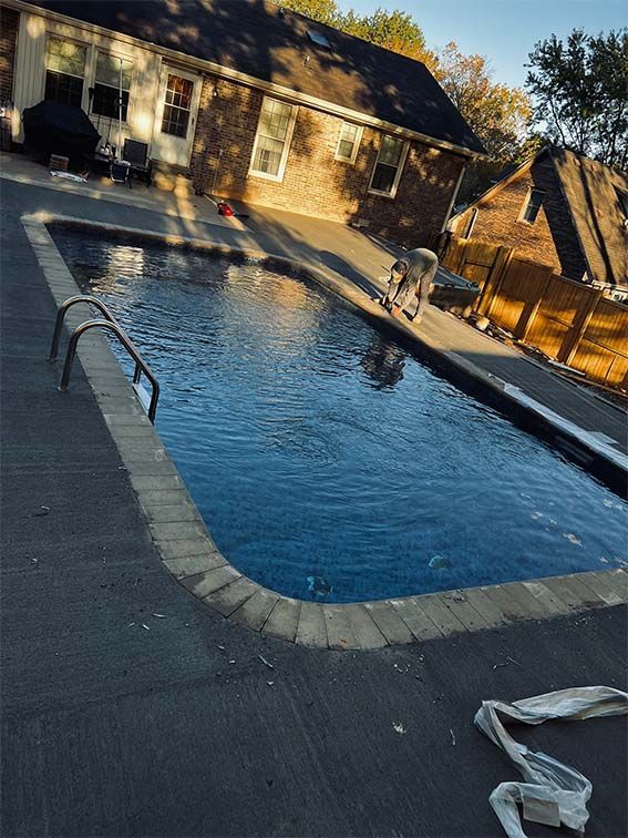 A large swimming pool is sitting in front of a house.