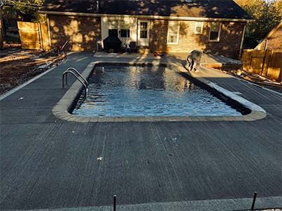 A large swimming pool is being built in the backyard of a house.