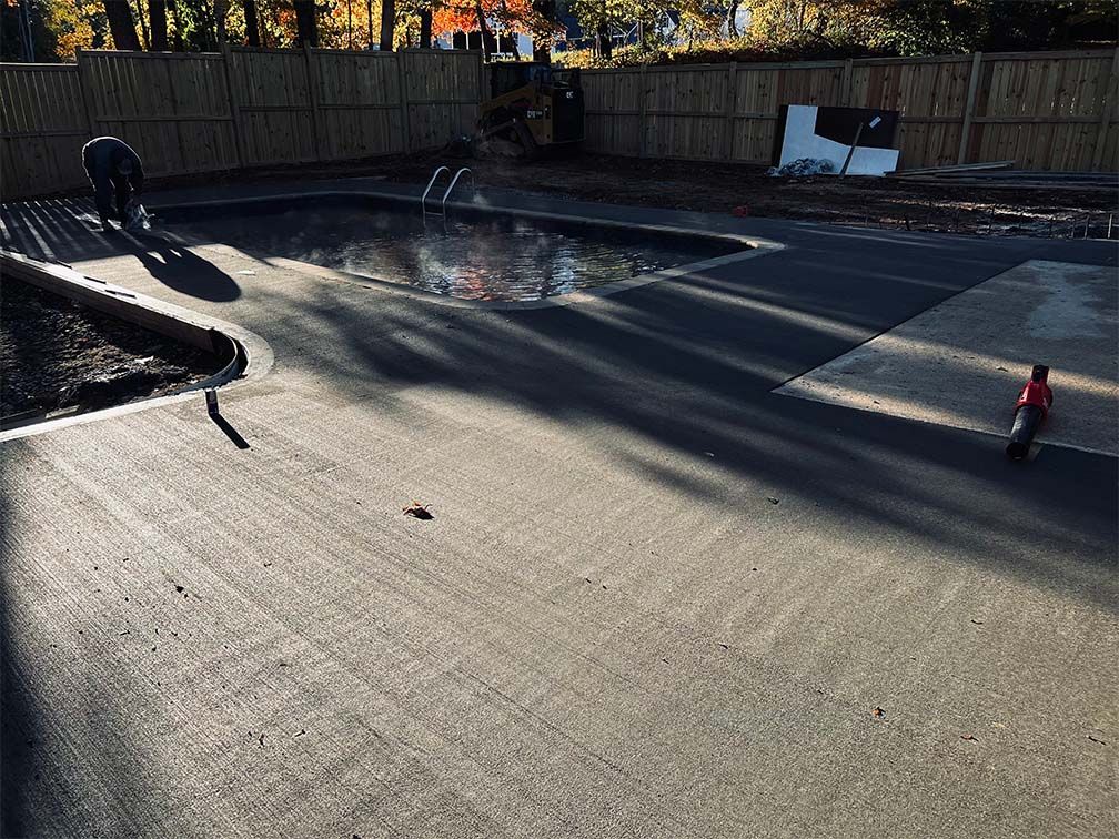 A person is standing next to a pool in a backyard.