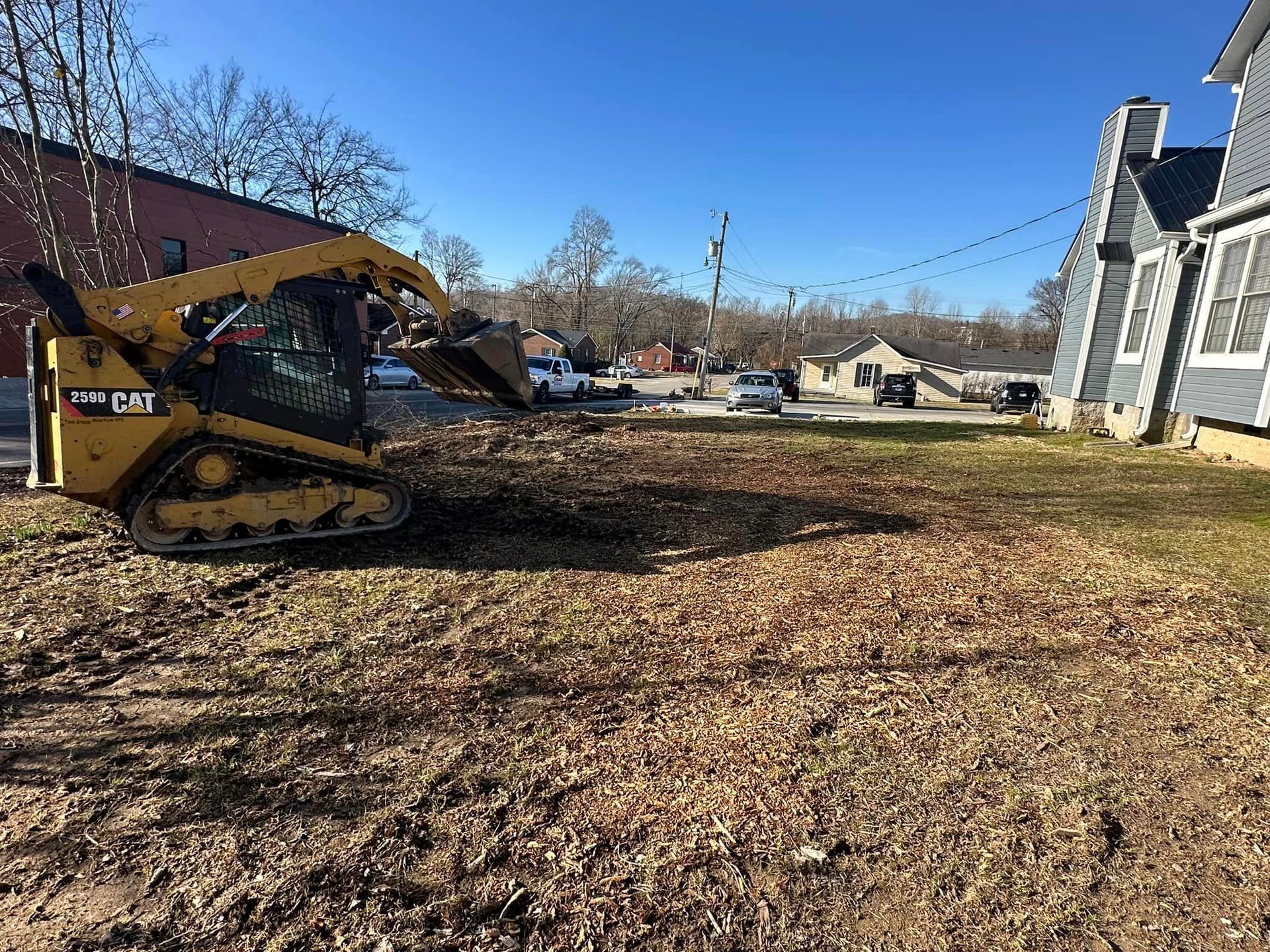 A bulldozer is sitting in the dirt in front of a house.