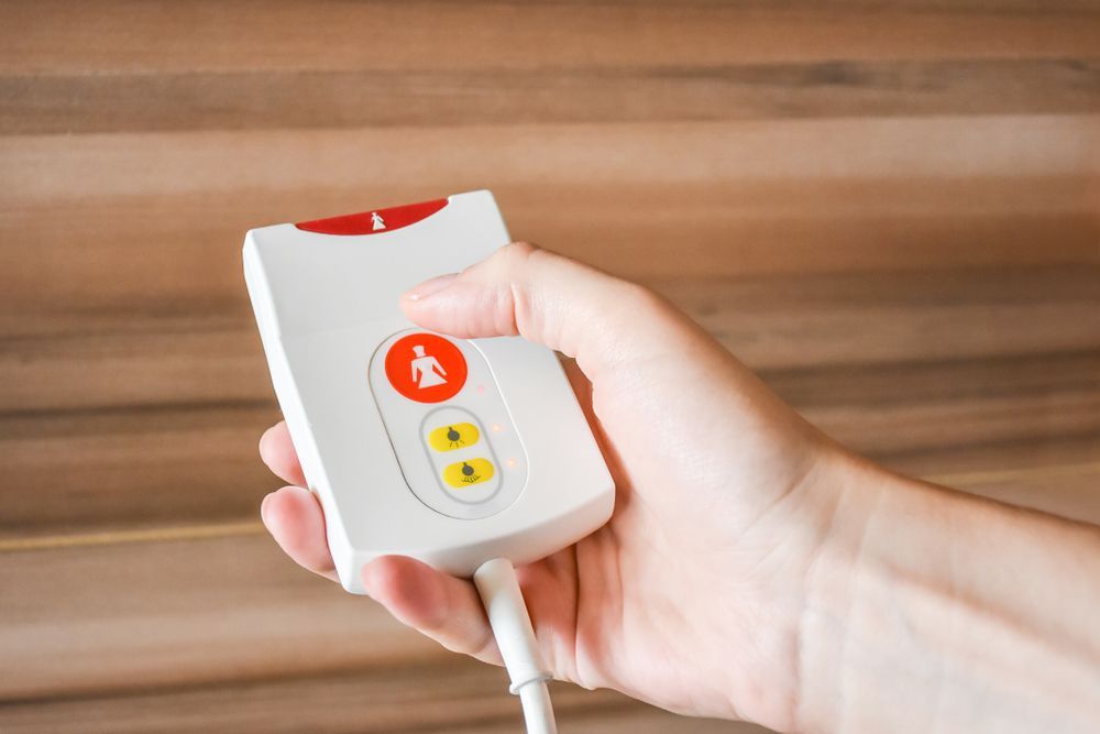 Hand Holding a White Emergency Call Button — NQ Video Surveillance in Mareeba, QLD