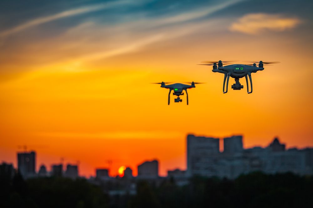Two Drones Silhouetted Against an Orange Sunset — NQ Video Surveillance in Mission Beach, QLD