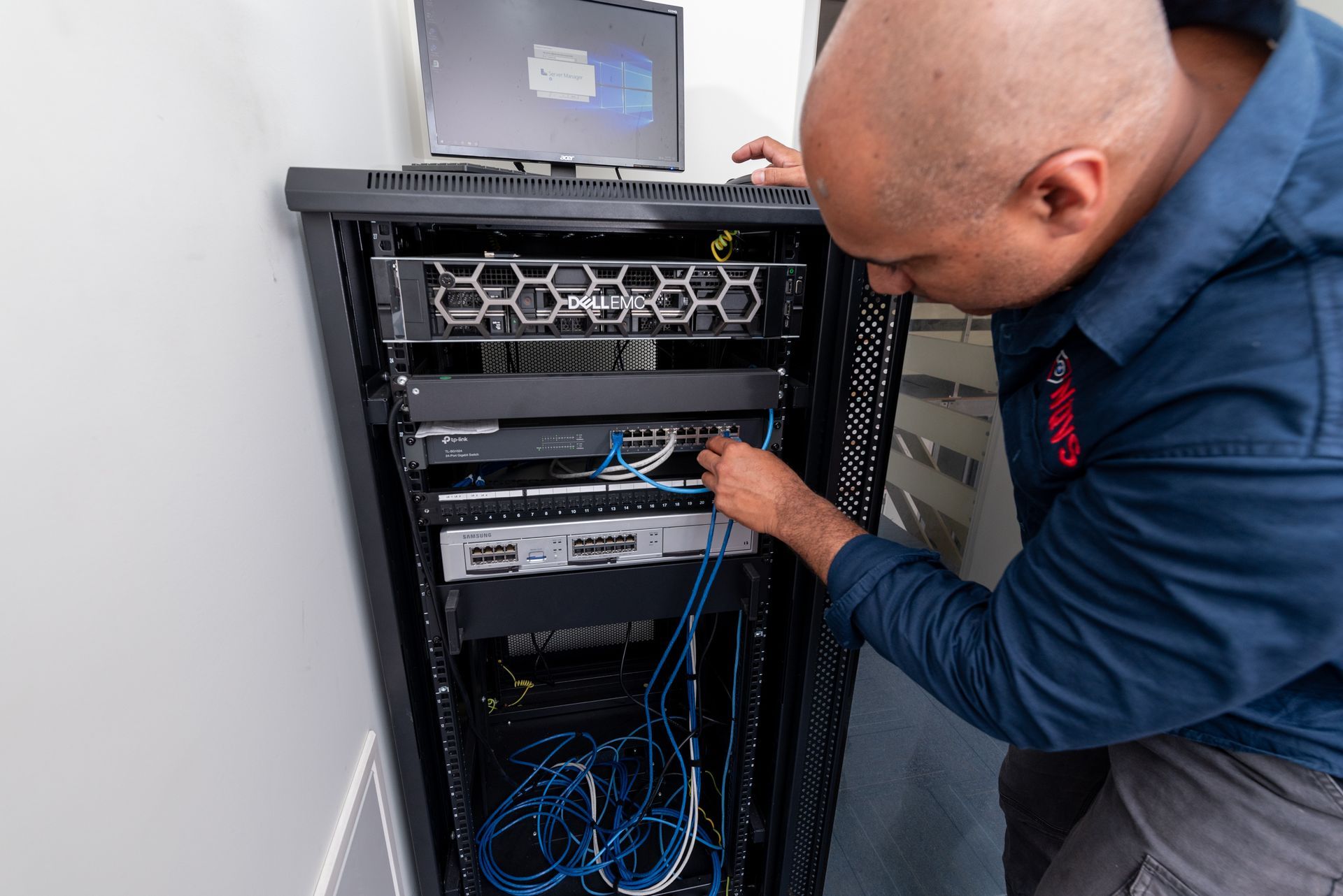 A Hand Holding a Black Handset Near a Wall-mounted Touch Screen — NQ Video Surveillance in Bungalow, QLD