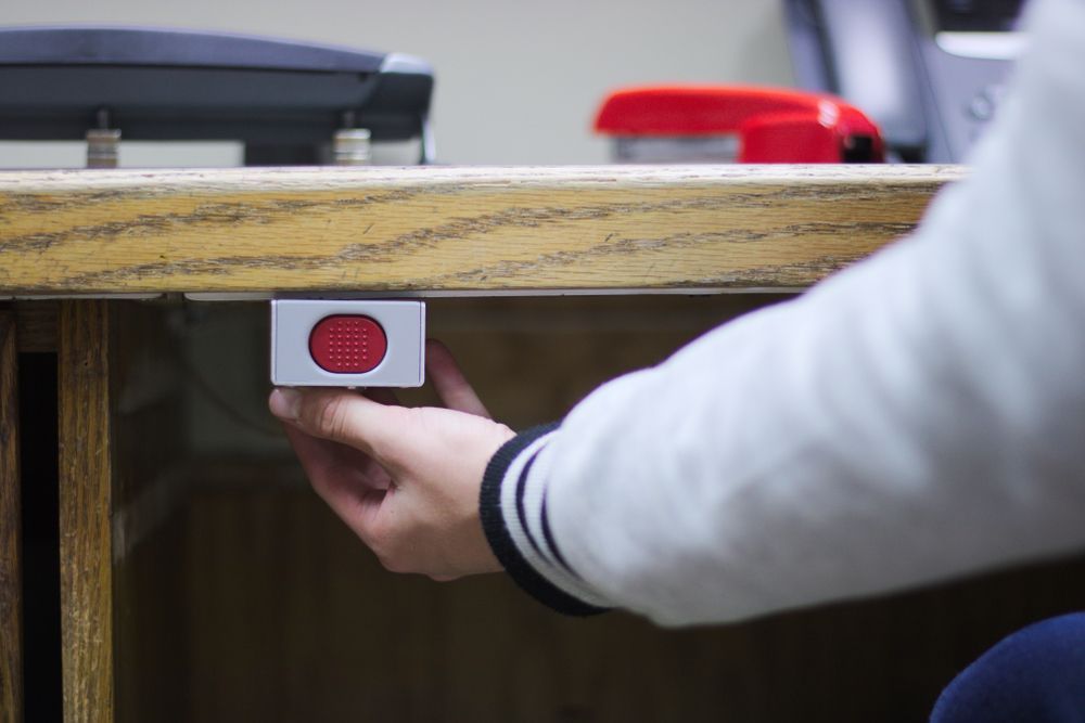 Person's Hand Reaching for a Red Button Mounted Under a Desk — NQ Video Surveillance in Bungalow, QLD