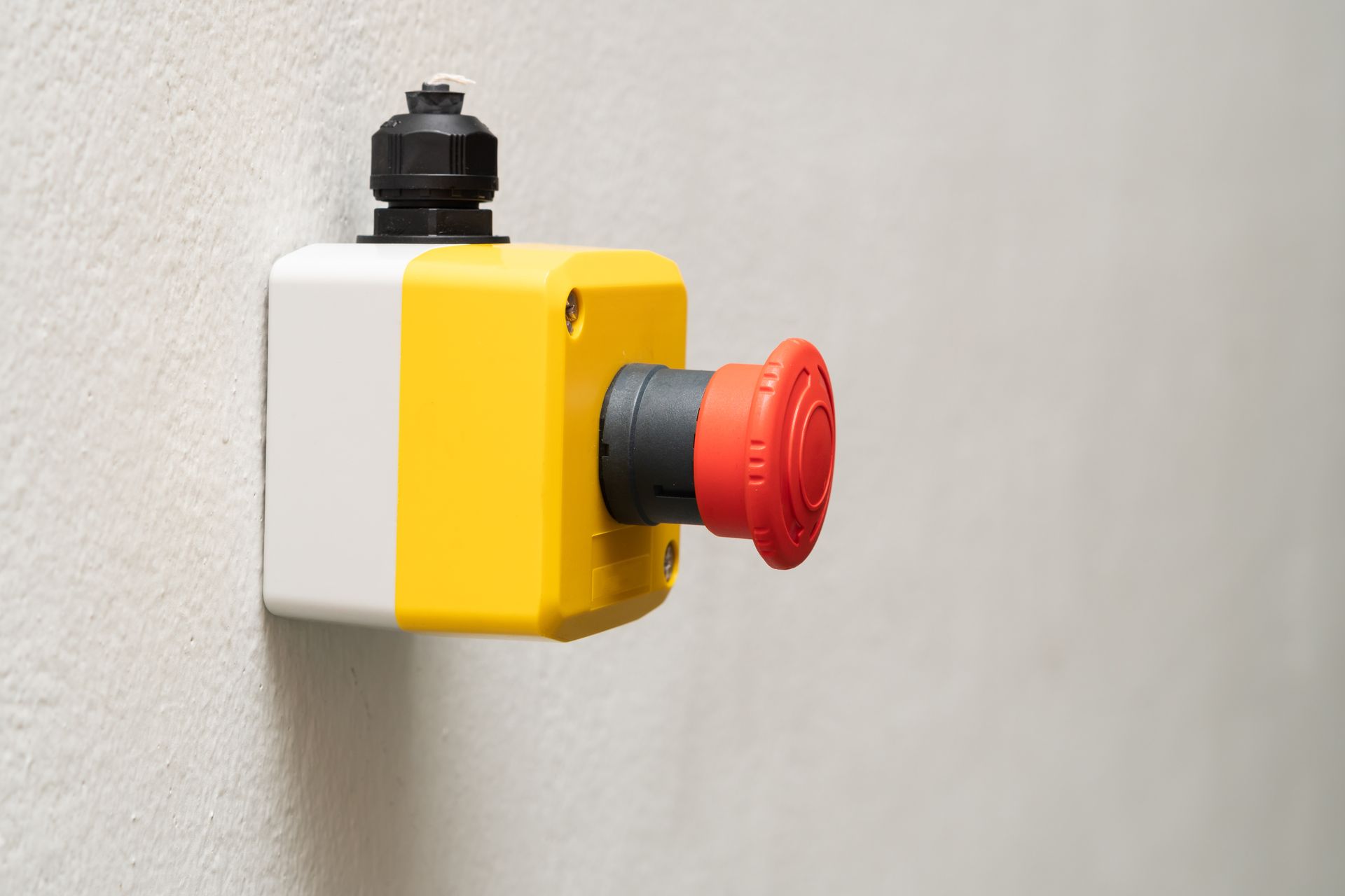 Yellow and White Emergency Stop Button on a Wall — NQ Video Surveillance in Mackay, QLD