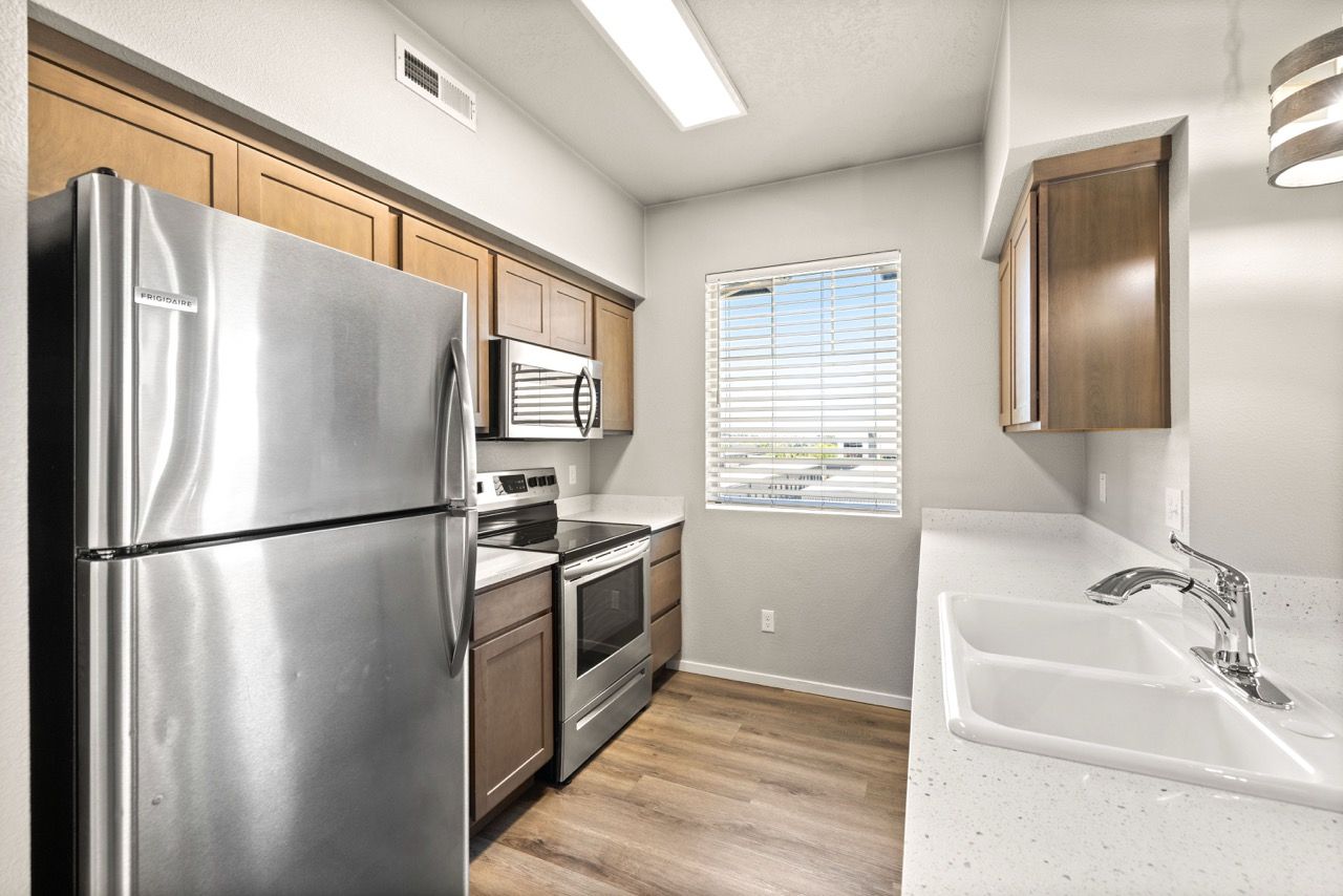 Apartment kitchen with stainless steel refrigerator, stove, microwave, and double sink.