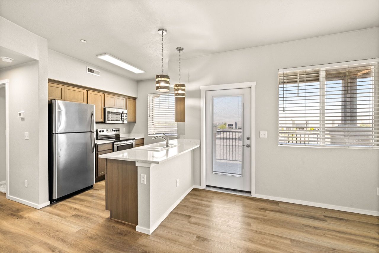 Open-concept kitchen with island, stainless steel appliances, and light wood cabinets.