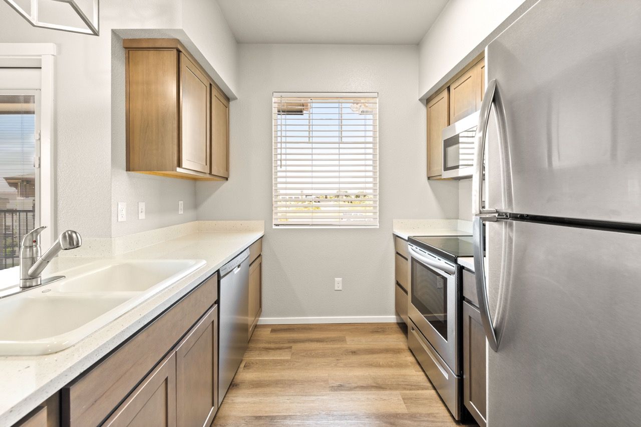 Modern apartment kitchen with stainless steel appliances and a window above the sink.