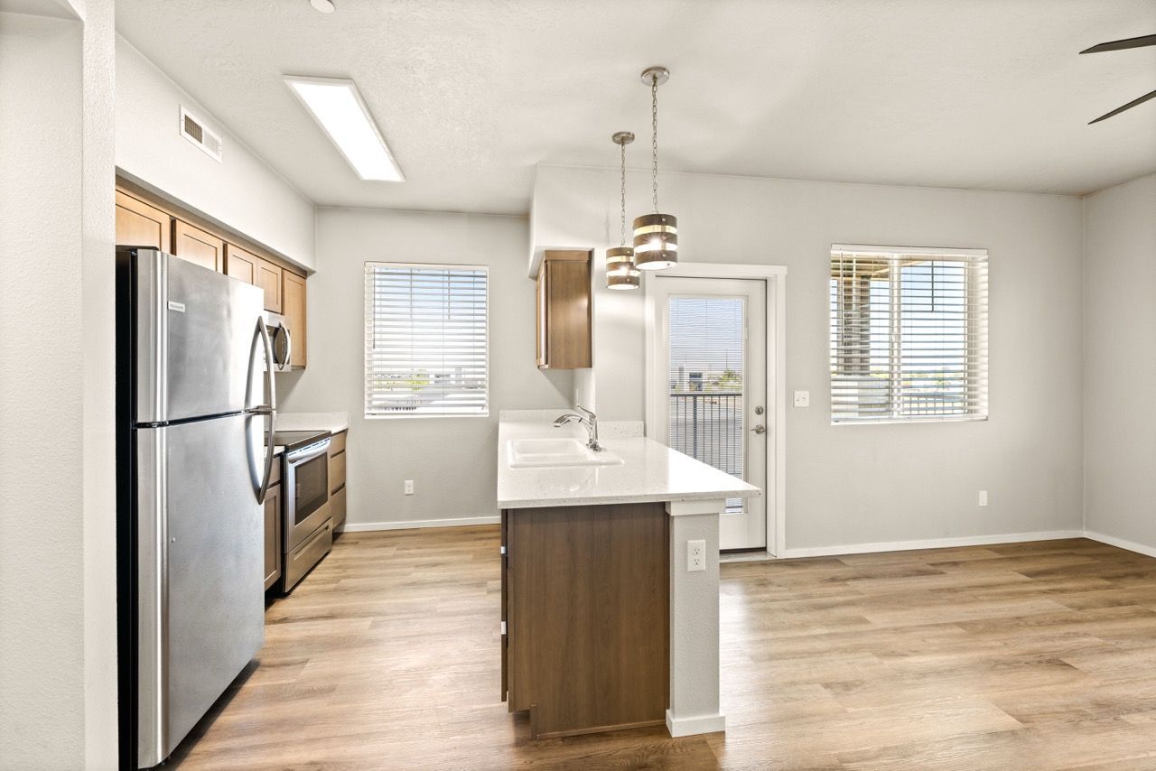 Bright modern kitchen with island, stainless steel appliances, and two pendant lights.